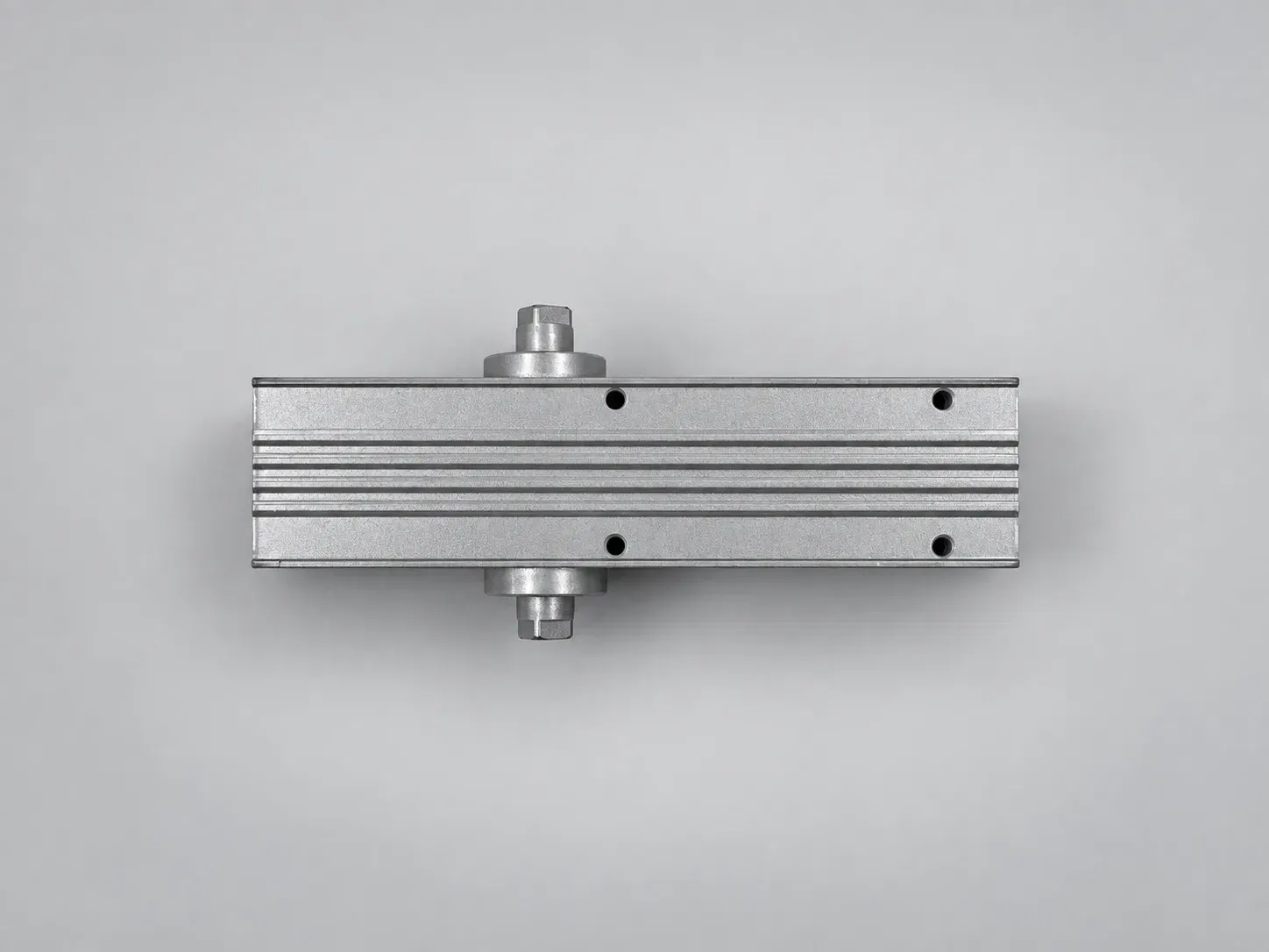 Extruded aluminium door closer body, grooved face with four fixing holes and both pinion ends, studio photograph